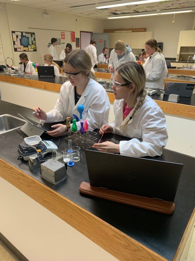 Two female Notre Dame students in science class looking at a tablet