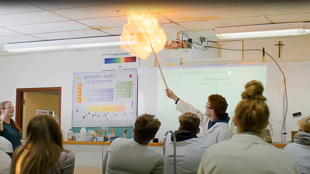 Science class with student holding a stick showing combustion